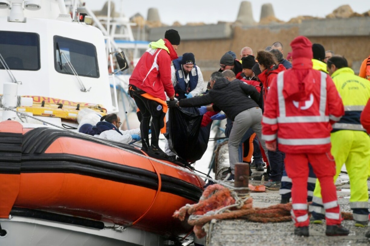 Des sauveteurs italiens débarquent le corps d'un migrant noyé dans le port d' Isola di Capo Rizzuto, près de Crotone, le 27 février 2023