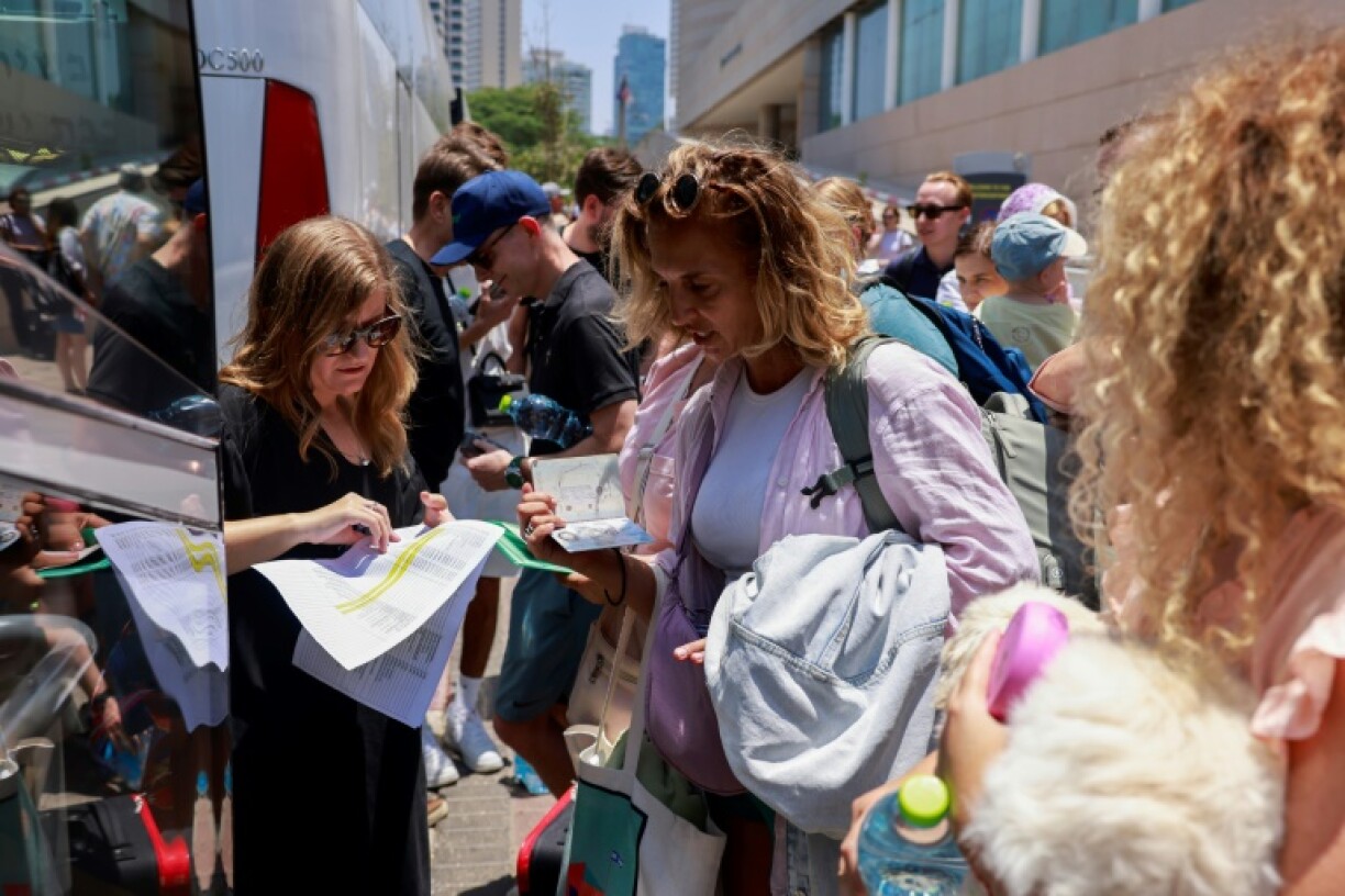 People register before the departure of a bus slated to evacuate foreign passport holders, mainly European, out of Israel, at a meeting point in Tel Aviv