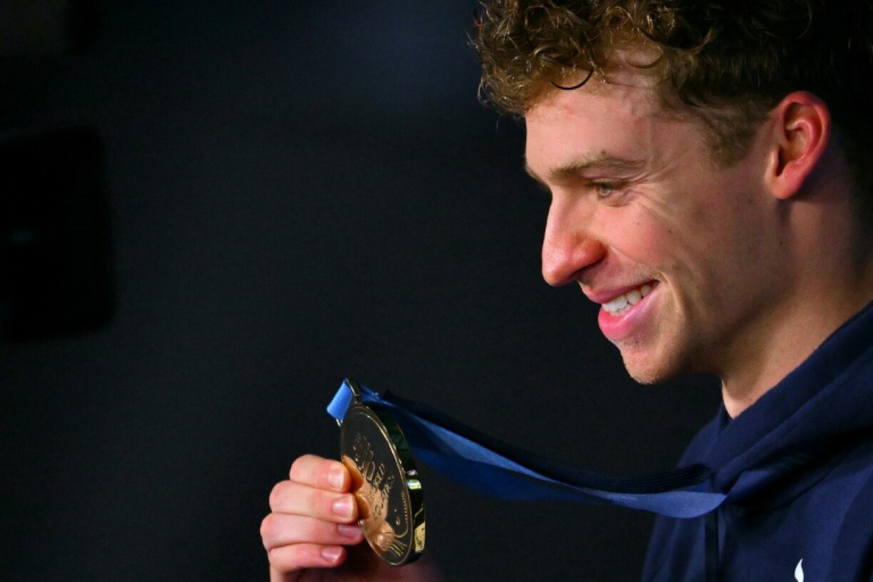 Leon Marchand celebrates on the podium of the men's 200m individual medley