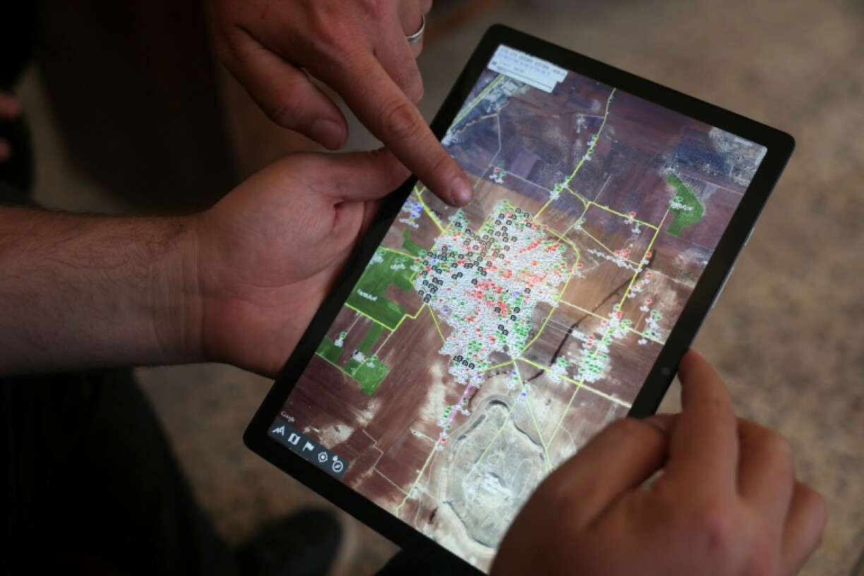 Syrian architect Abdel Aziz al-Mohammed (L) shows on a tablet an interactive map that he created, revealing the detailed conditions of each house in his village Tal Mardikh