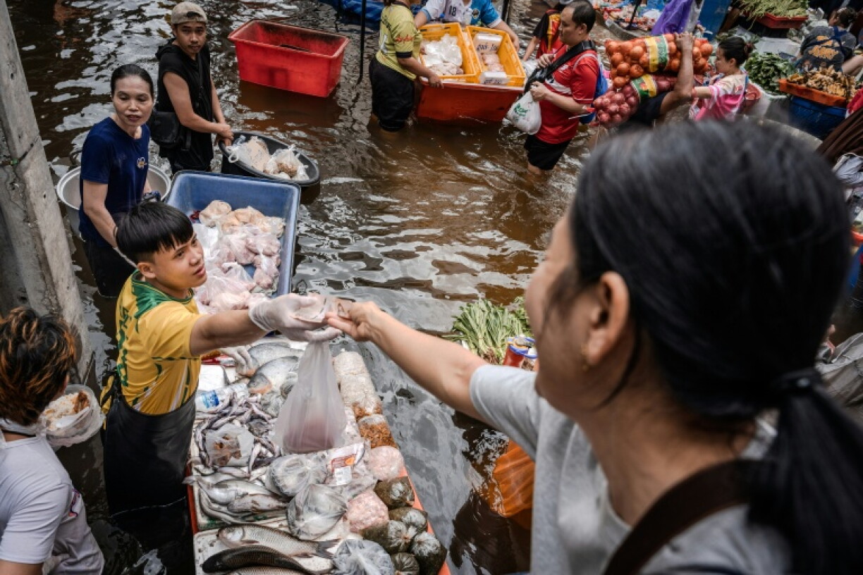 Stallholders sell everything from pork mince to bananas along what should be a street, but is now a murky river