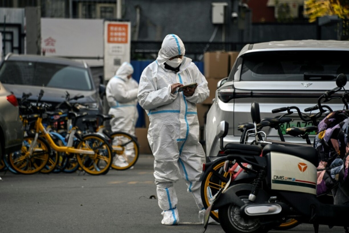 Du personnel de sécurité en combinaison de protection patrouille dans une rue de Pékin, le 23 novembre 2022