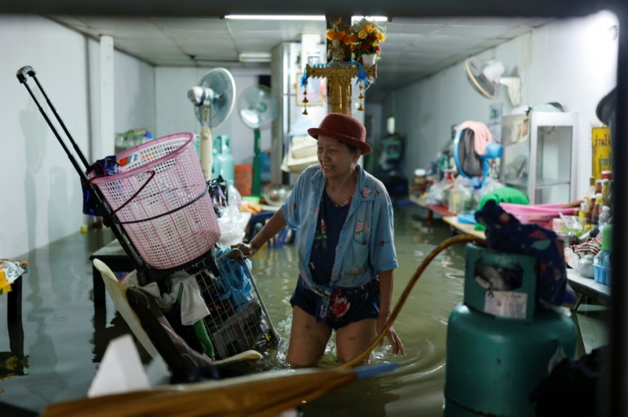 Une personne s'occupe de sa boutique inondée dans le district de Bang Bua, à Bangkok, le 26 septembre 2026