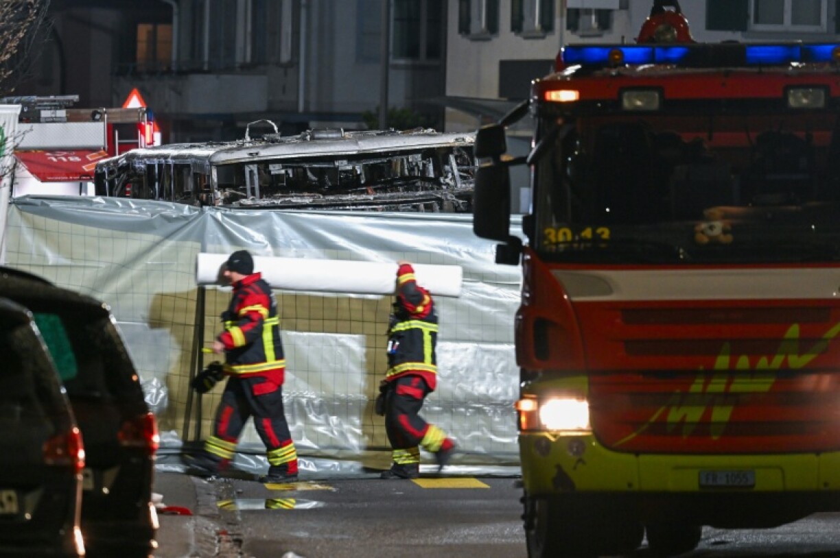 Des pompiers autour de l'autocar qui a pris feu faisant plusieurs morts, à Chiètres (Kerzers, en allemand), en Suisse, le 10 mars 2026