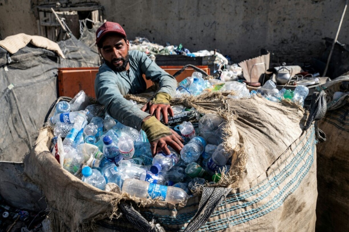 An Afghan worker loads plastic bottles into a sack at a recycling yard in Kabul