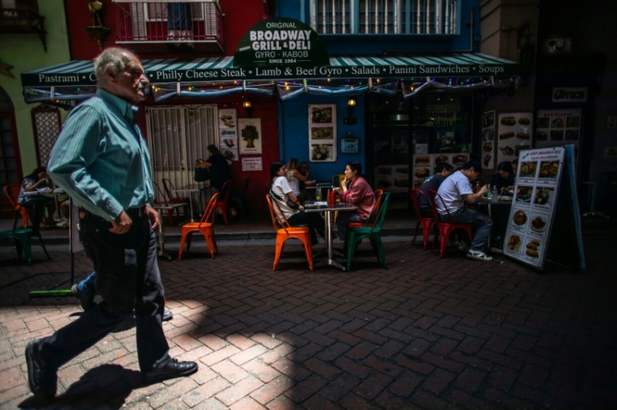 A man walks by past a restarant while people have lunch on a sunny June day in protest-hit Los Angeles