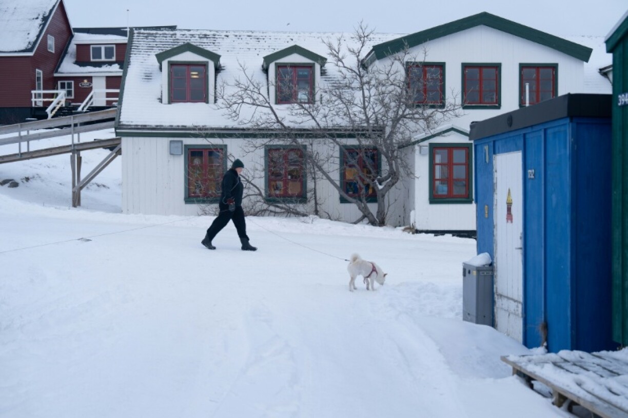 Une femme promène son chien dans le quartier du Vieux Nuuk, à Nuuk, au Groenland, le 16 janvier 2026