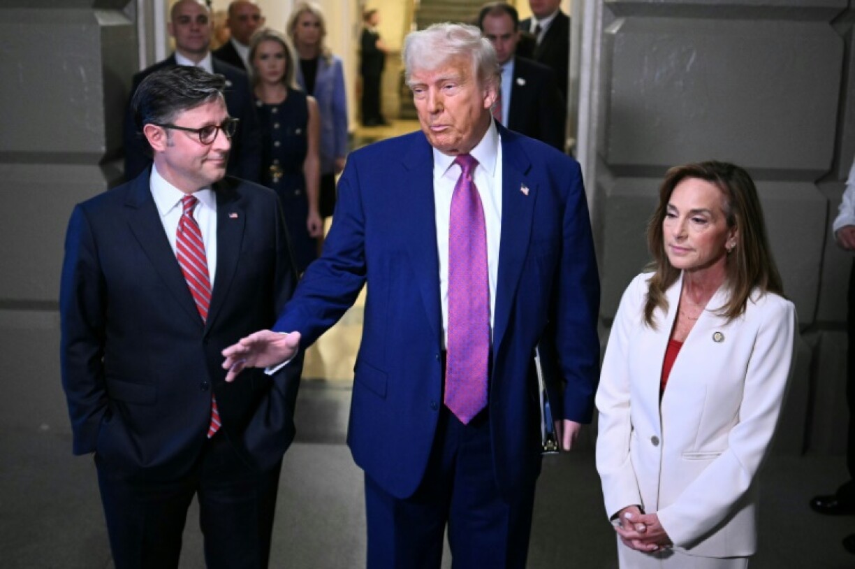 US President Donald Trump, joined by US Speaker of the House Mike Johnson (L) and US House Republican Conference Chair Lisa McClain (R), speaks to reporters as he arrives for a House Republican meeting to build support for a sweeping tax cut bill