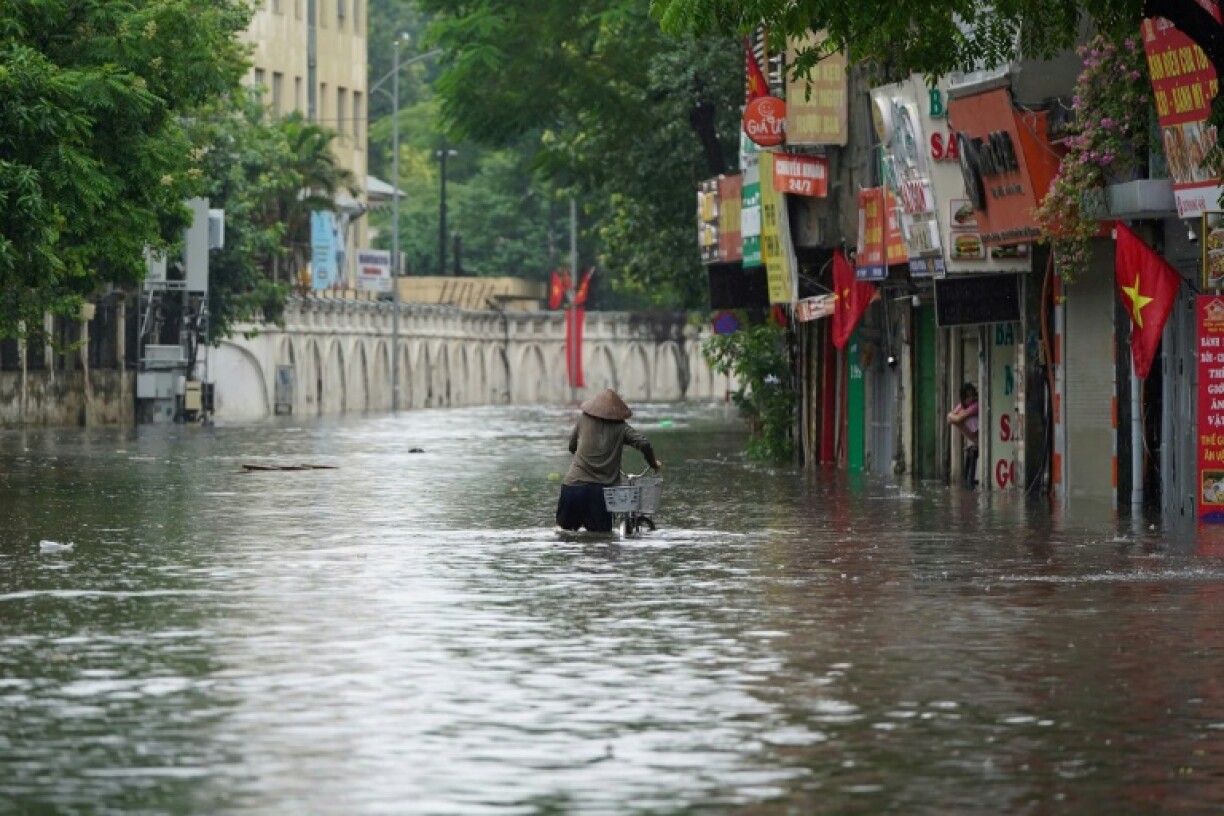 Une habitante pousse son vélo dans une rue inondée à Hanoï, après le passage du typhon Kajiki, le 26 août 2025 au Vietnam