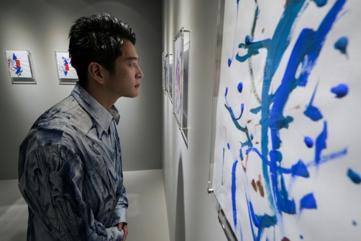 Gallery director Dan Isomura posing with abstract artwork on display by 21-month-old artist