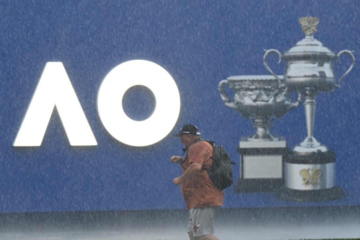 A man walks in heavy rain beside on day one of the Australian Open