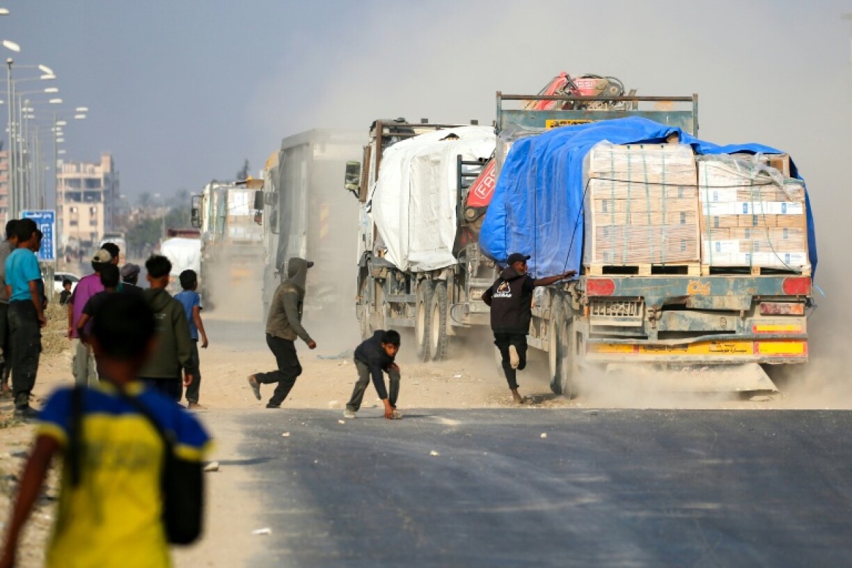 Un Palestinien tente de monter à bord d'un camion circulant sur la route Salah al-Din, dans le centre de la bande de Gaza, près de Deir al-Balah, alors que des personnes tentent d'obtenir de l'aide humanitaire, le 9 novembre 2025