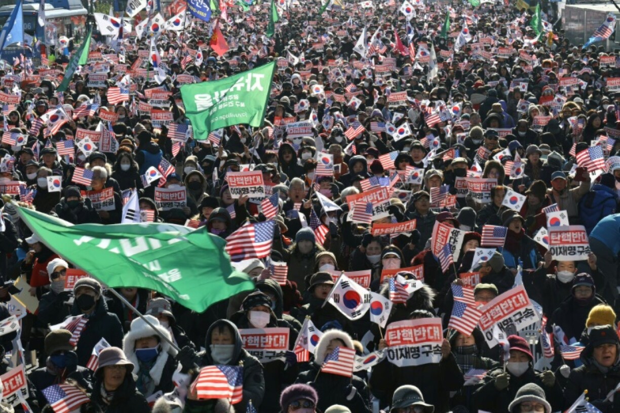 Yoon supporters wave South Korean and US flags and hold signs reading 'Against impeachment... arrest Lee Jae-myung'