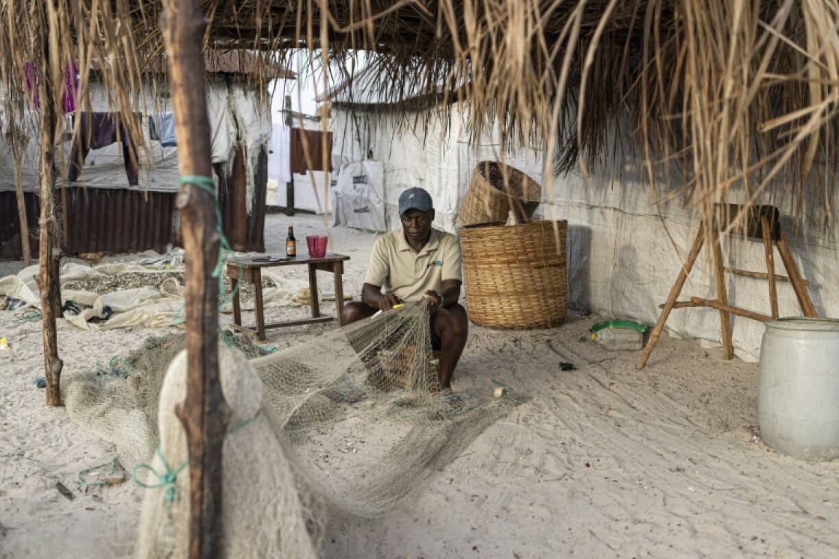 Community chief Amidou Bureh fixes a fishing net outside his home on Nyangai island