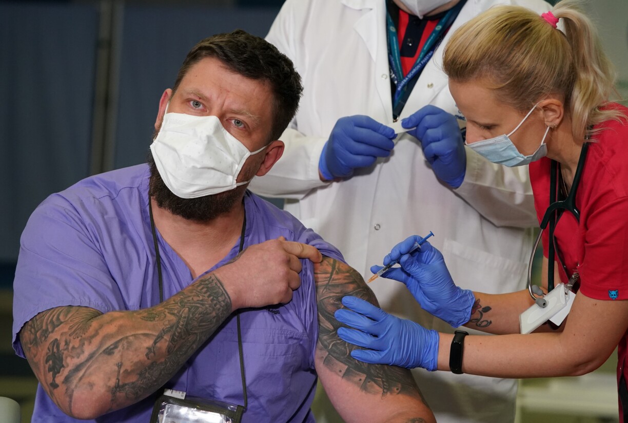 Slawomir Butkiewicz (L), member of rescue team against the novel coronavirus COVID-19, is given a dose of the Pfizer-Biontech Covid-19 corona virus vaccine by Doctor Agnieszka Szarowska in Warsaw, Poland, on December 27, 2020.