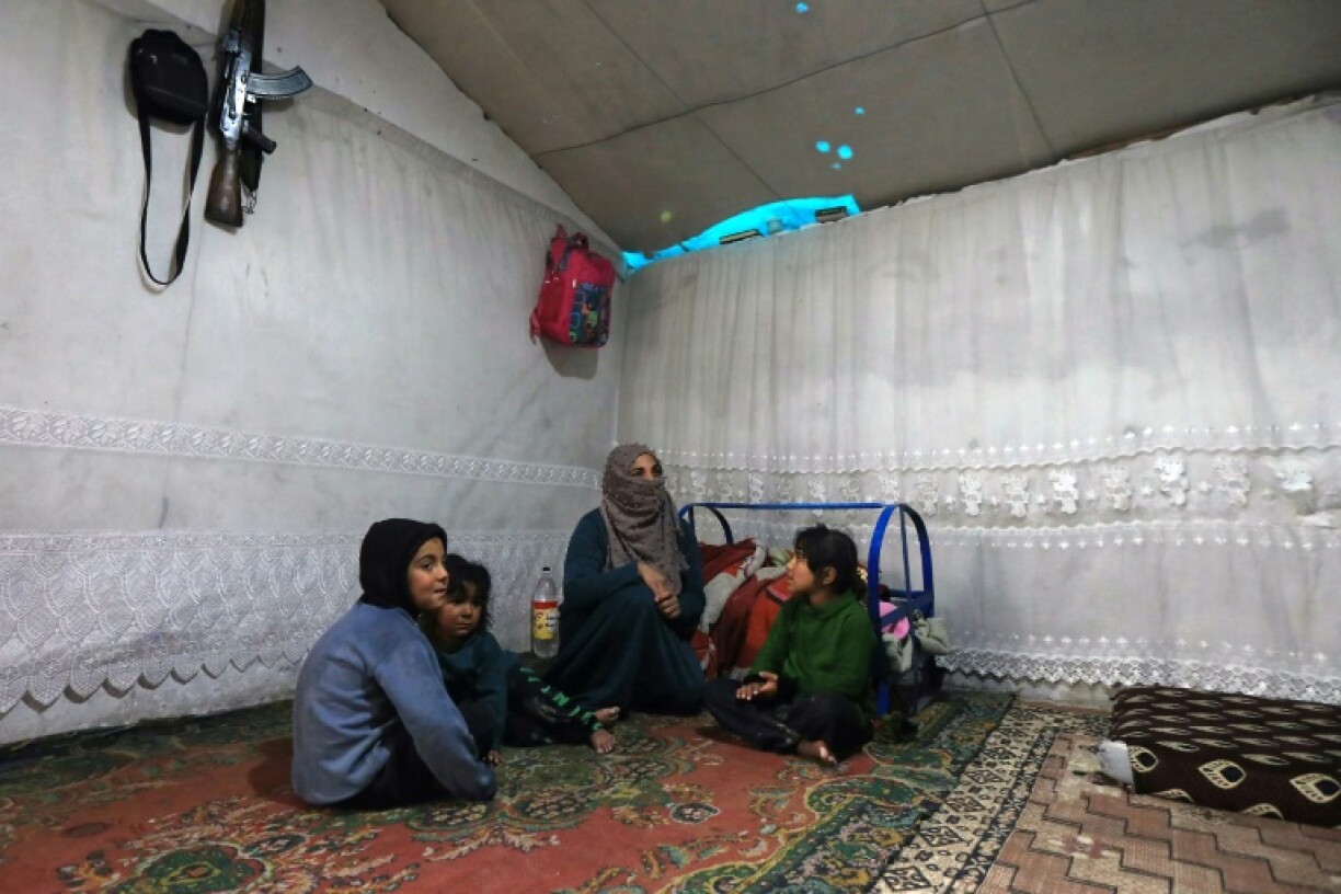 An AK-47 assault rifle hangs on the wall of a home in the Atme camp