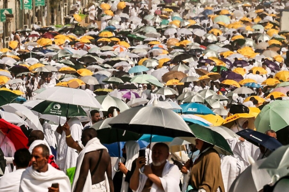 Muslim pilgrims use umbrellas to shade themselves from the sun