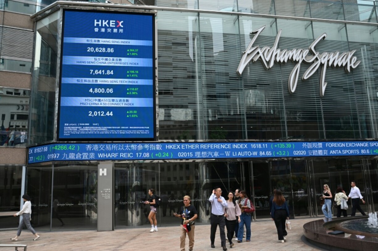 People pass an electronic sign showing the price of the Hang Seng Index at Exchange Square in Hong Kong on April 10, 2025