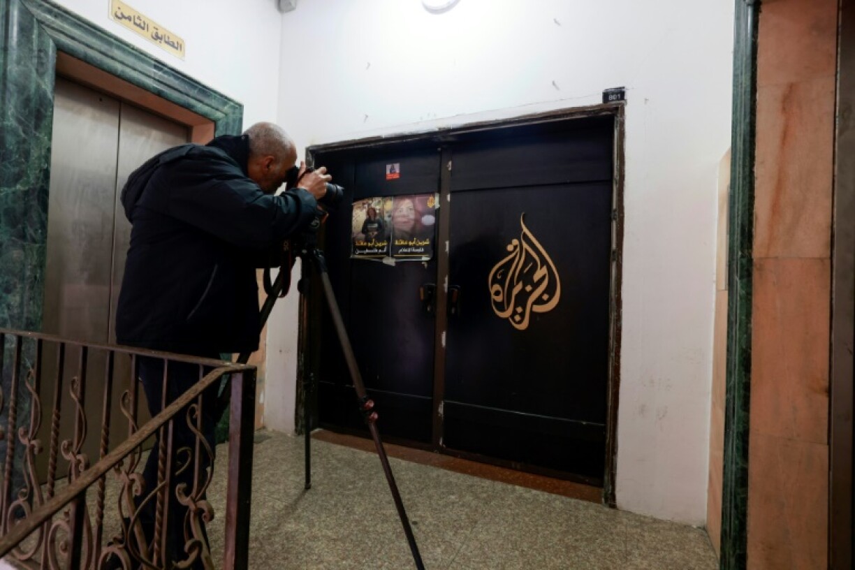 A photographer shoots the closed door of Al Jazeera TV's office in the Israeli-occupied West Bank city of Ramallah following a suspension order from the Palestinian Authority