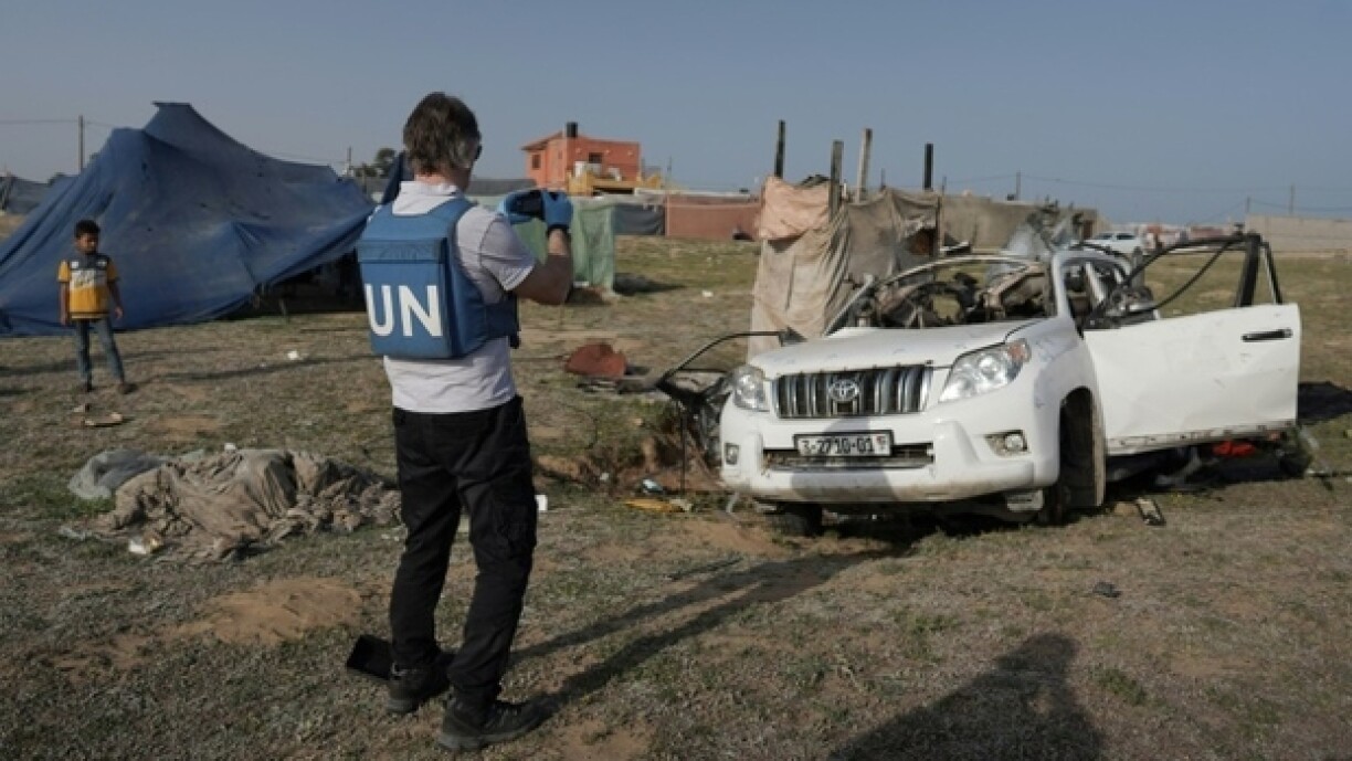 Des membres du personnel des Nations Unies inspectent la voiture dans laquelle voyageaient des humanitaires étrangers, tués par une frappe israélienne, le 2 avril 2024 à Deir al-Balah, dans la bande de Gaza