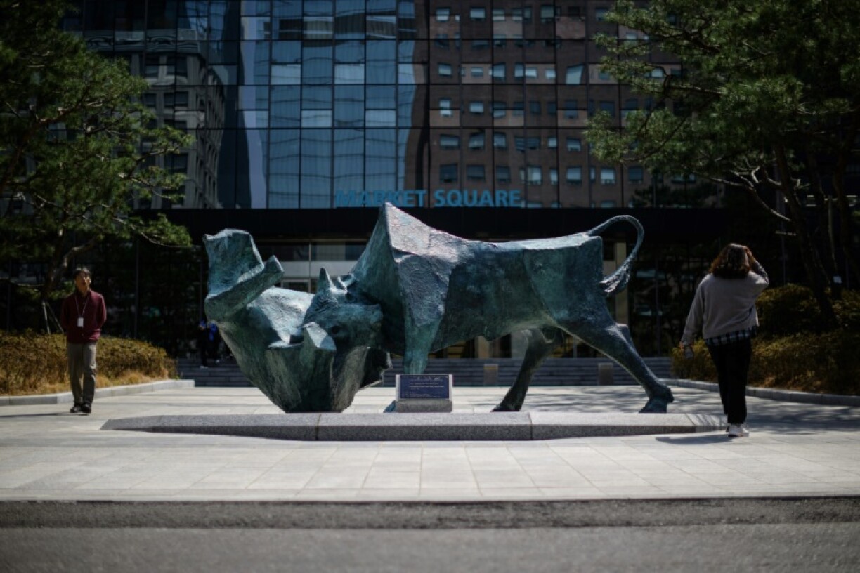 People walk past a bull and bear sculpture in front of the Korea Exchange building in Seoul