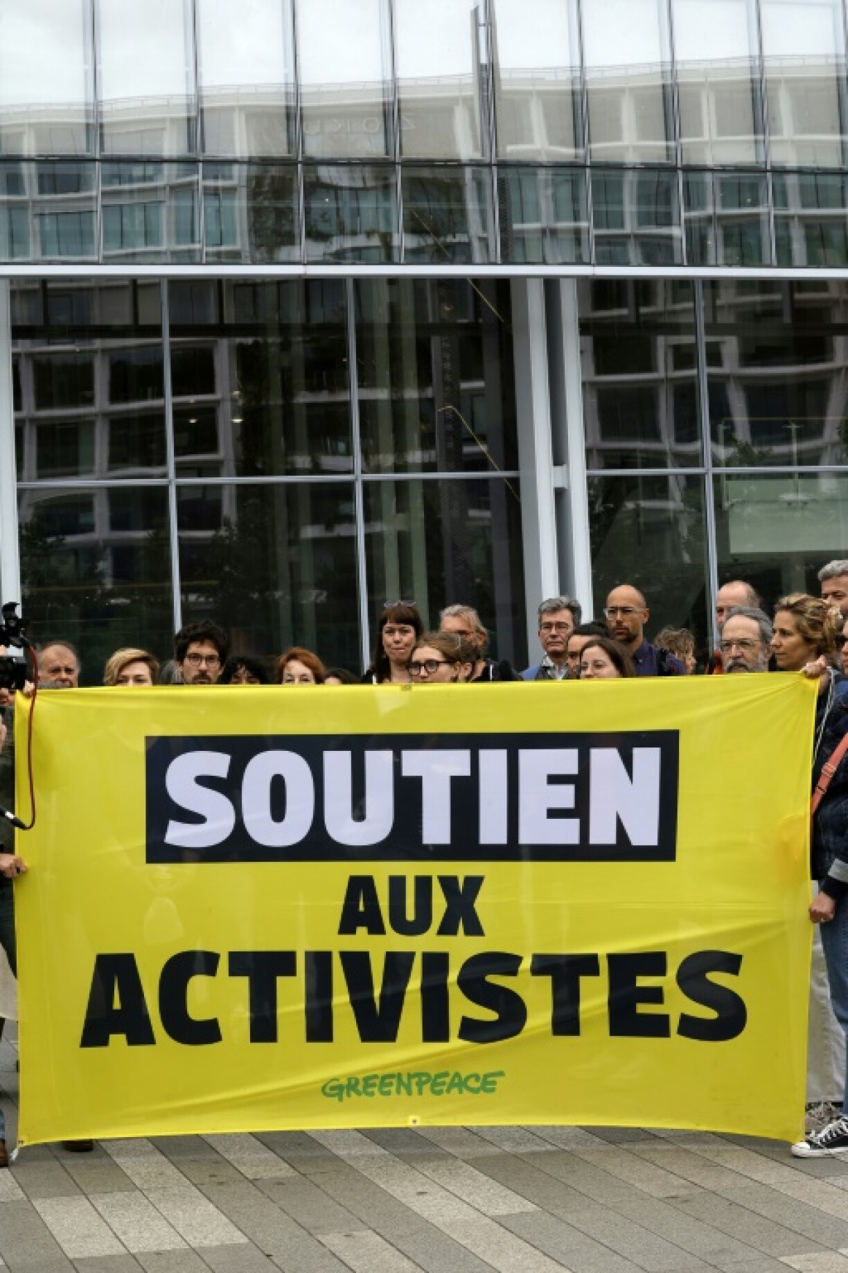 Supporters in Paris hold a banner during a rally to experss solidarity with two Greenpeace activists charged with theft