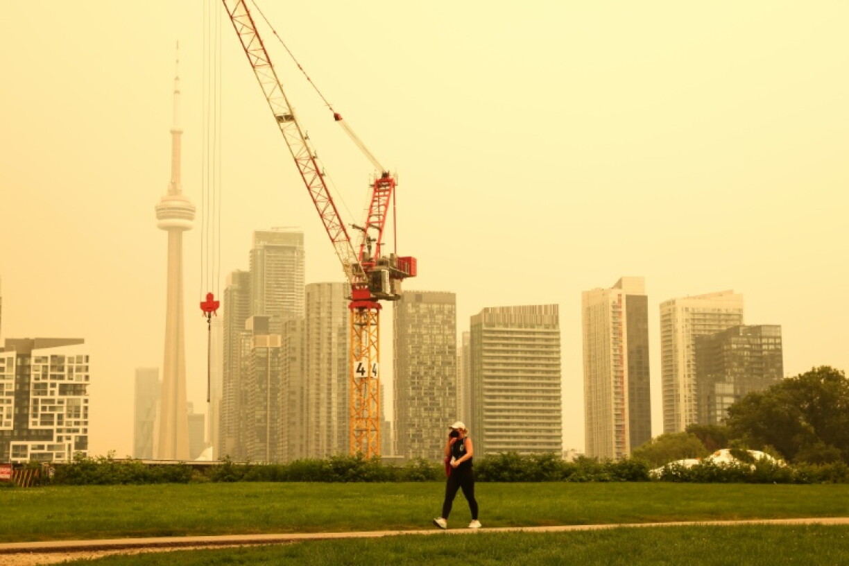 A person walks by the skyline of downtown Toronto, as smoke from forest fires in Northern Ontario causes poor air quality over the city, in Toronto, Ontario, Canada, Wednesday, July 15, 2026.