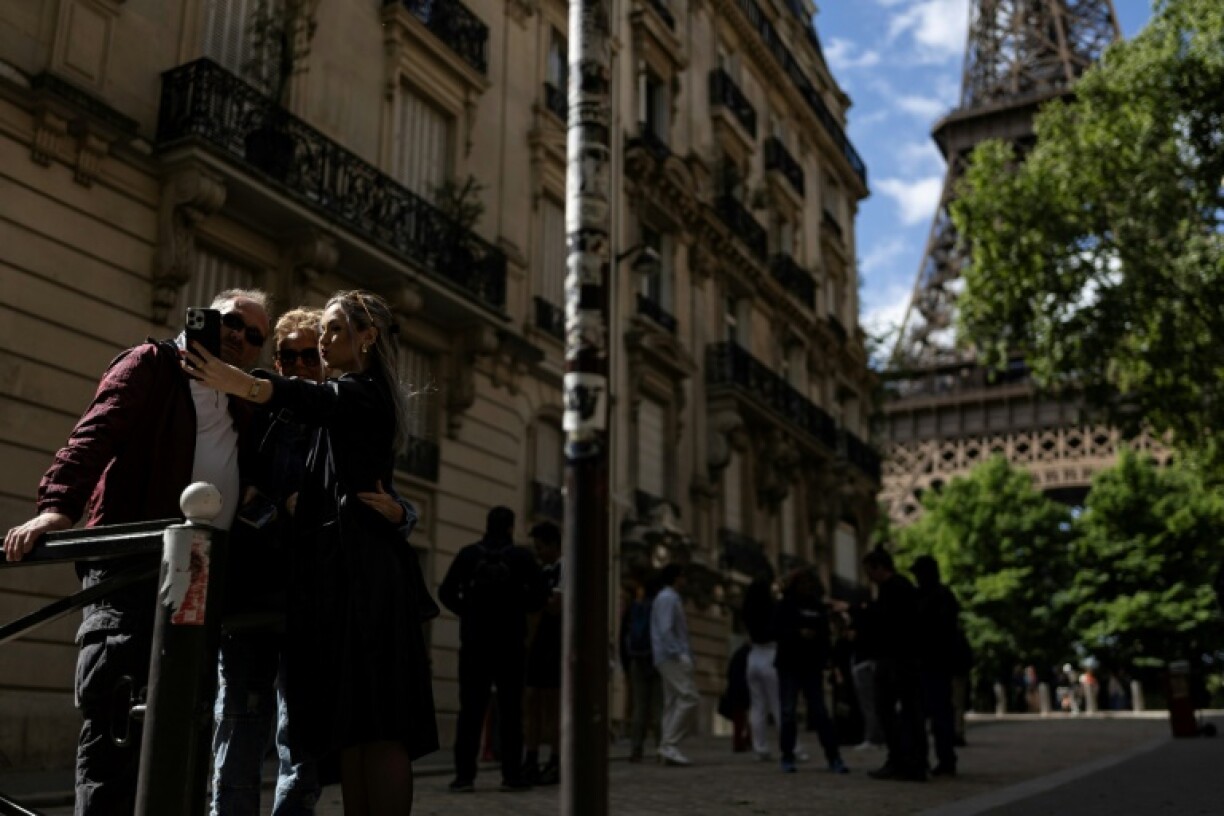 Three pedestrians take a selfie on the picturesque alleyway at the end of Rue de l'Universite, Paris
