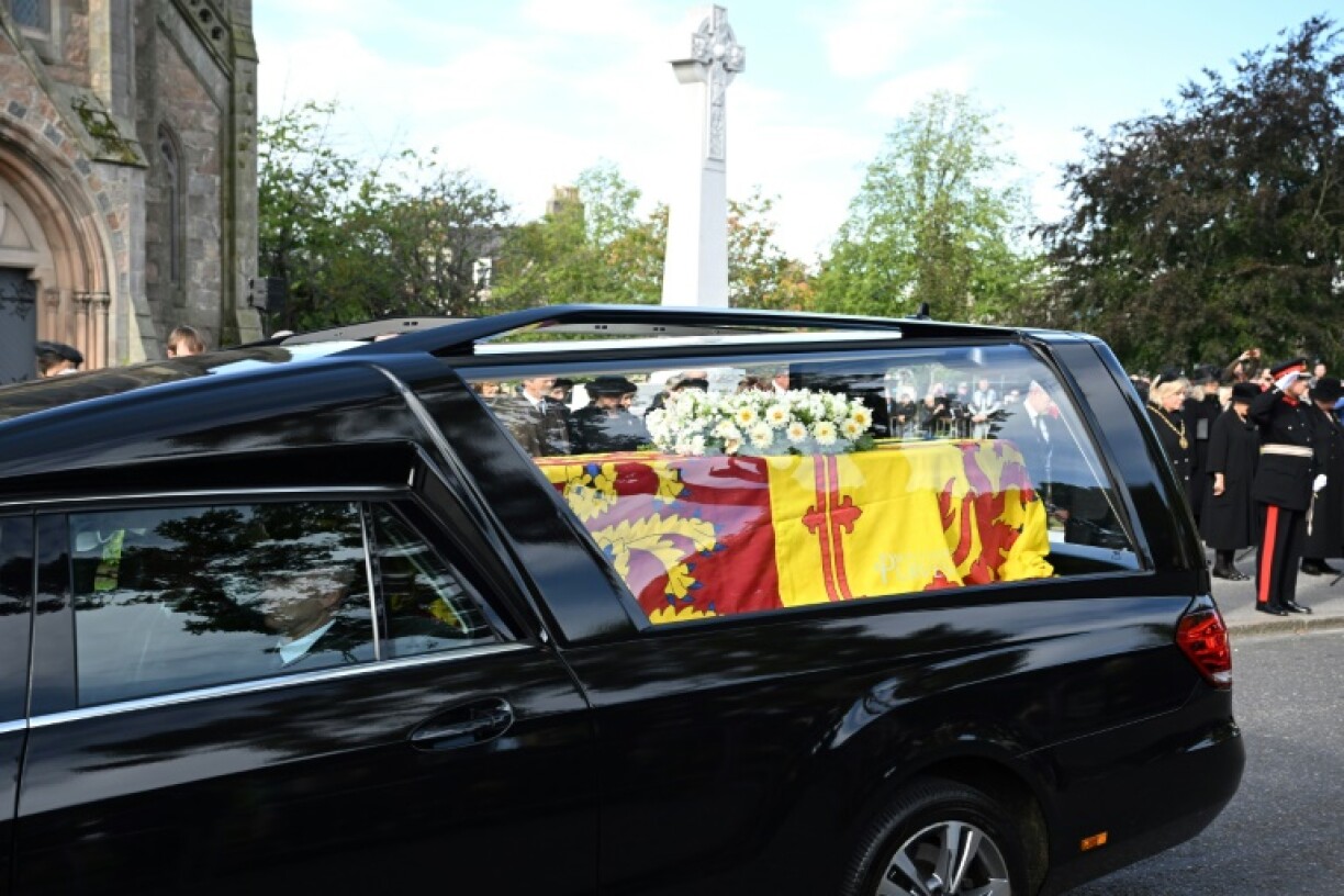 Des spectacteurs rendent hommage au cortège transportant le cercueil de la reine Elizabeth II, recouvert de l'étendard royal écossais, à Ballater, le 11 septembre 2022.
