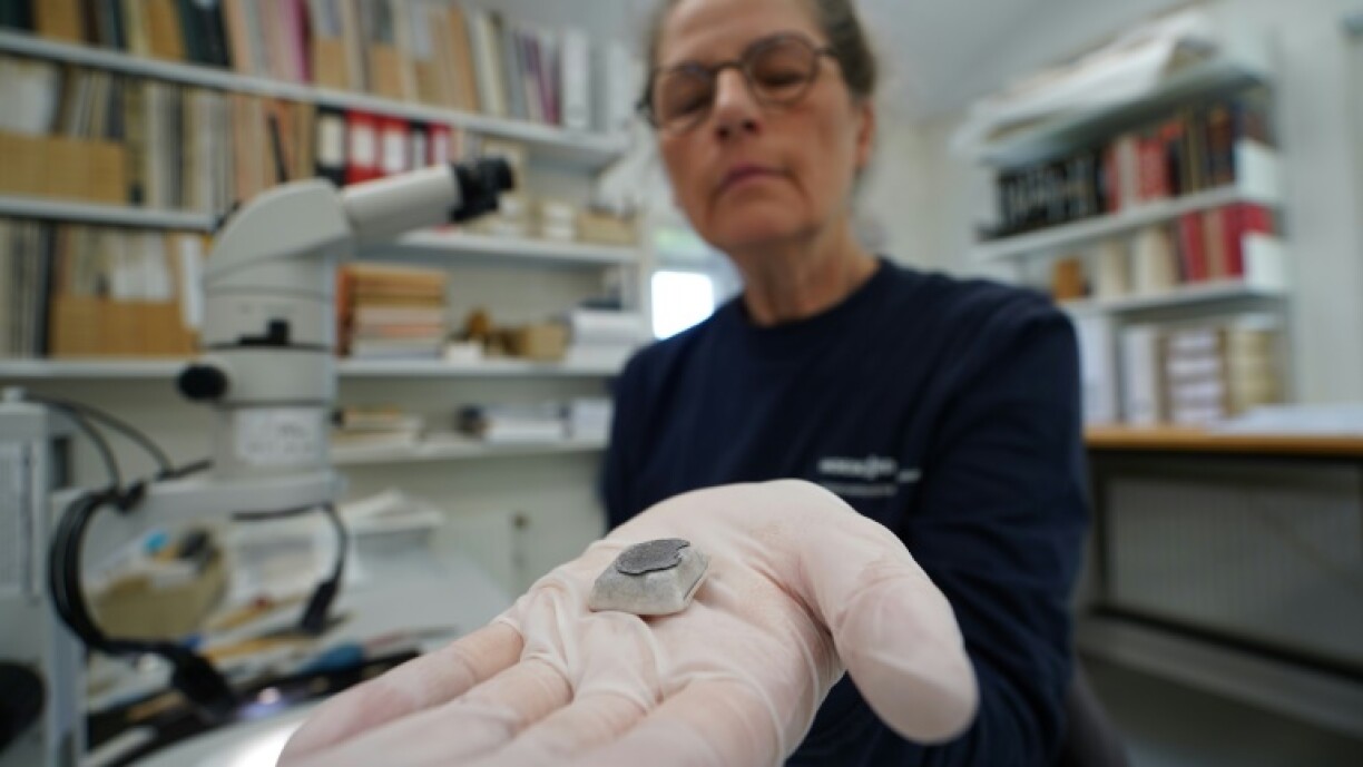 Conservator Helle Strehle holds a Viking Age silver coin from the site, where experts say a trove of 'spectacular' objects have been found