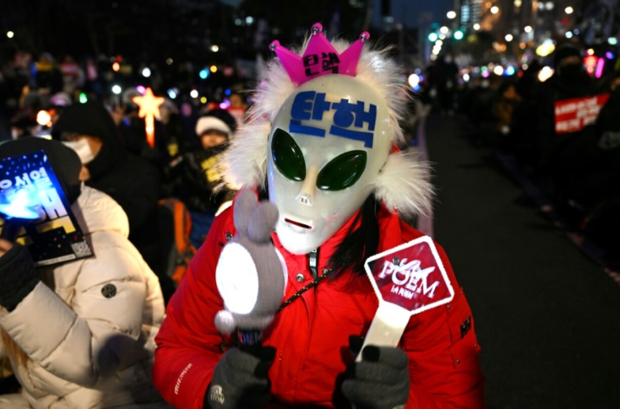 A man wearing a mask with the word 'impeachment' written on it takes part in a protest calling for the ouster of South Korean President Yoon Suk Yeol
