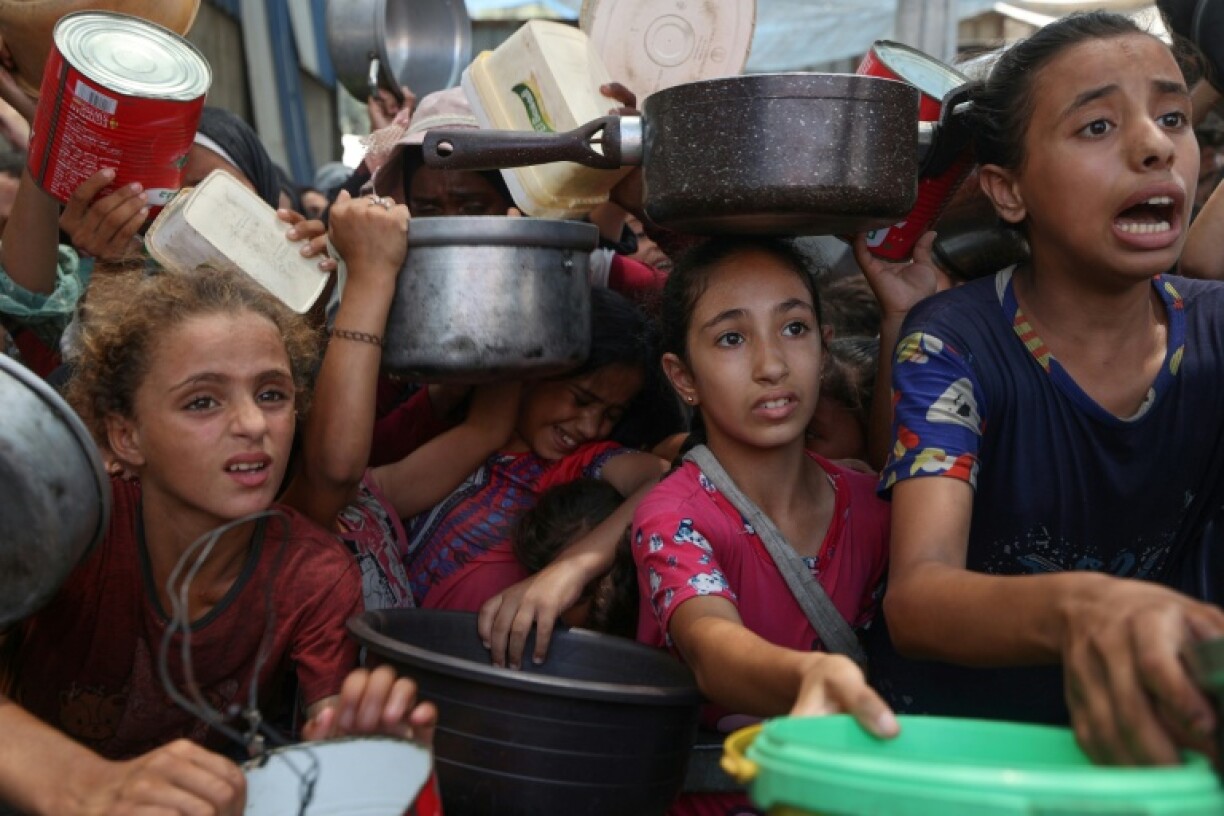 Palestinians gather to receive cooked meals from a food distribution center in the Nuseirat refugee camp in the central Gaza Strip on August 18, 2025