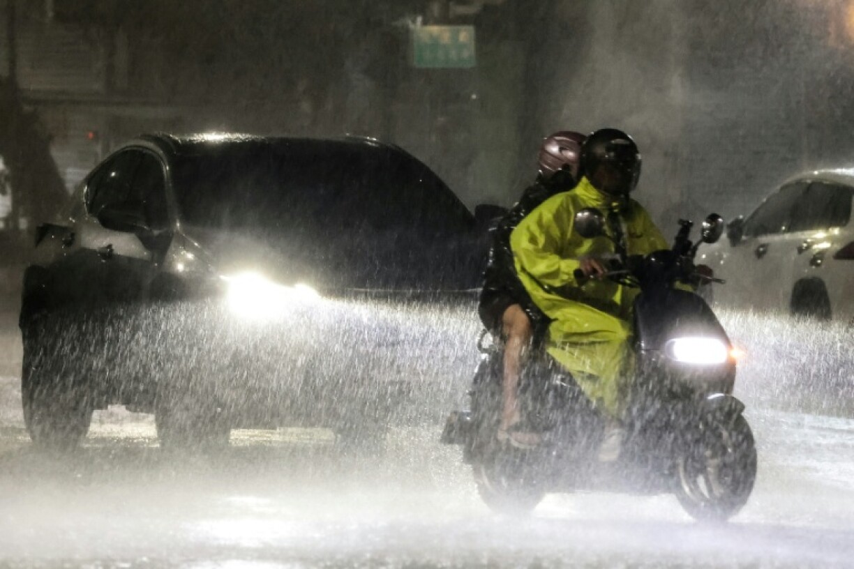 A people ride a motorcycle amid heavy rain brought by Typhoon Podul in Kaohsiung, Taiwan