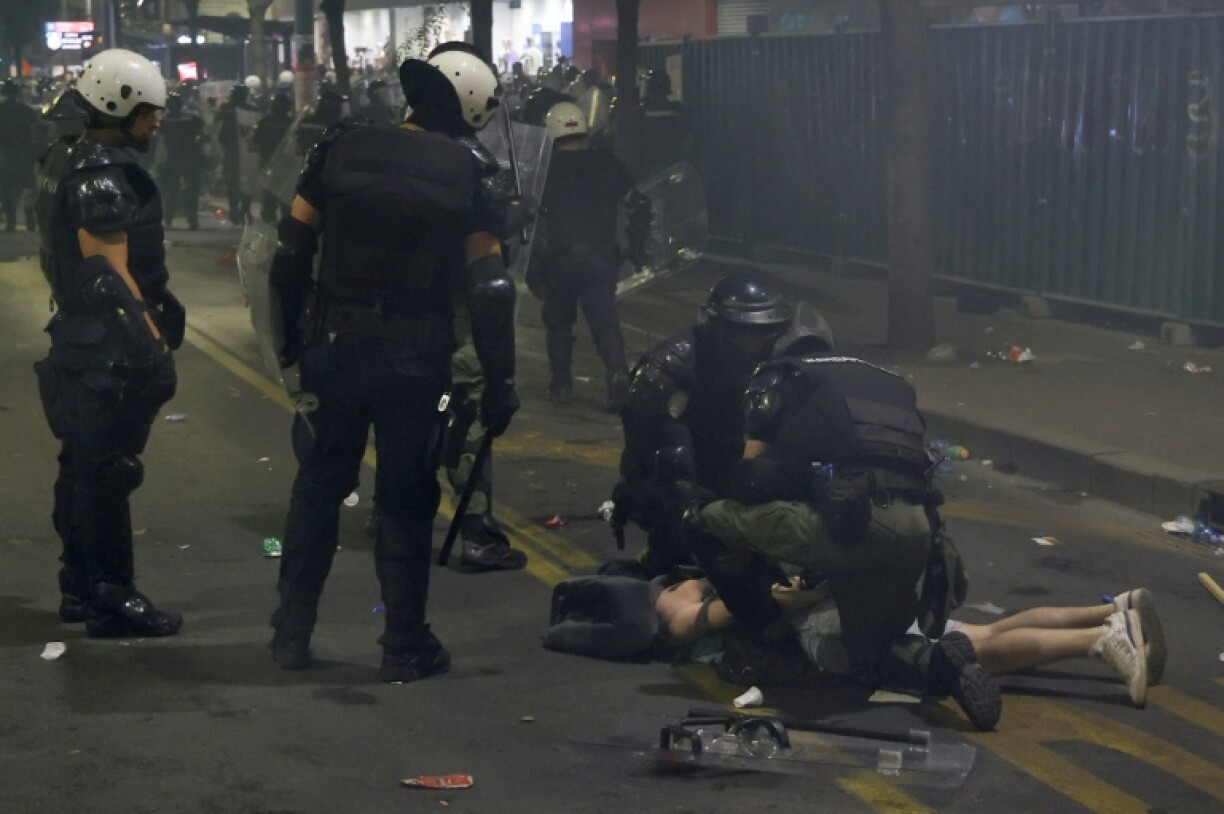 Serbian Riot Police officers arrest a man as tens of thousands of protesters gather in central Belgrade