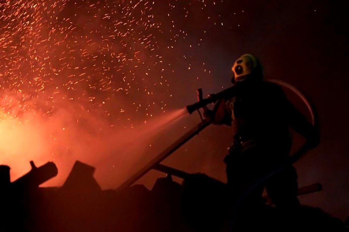 A Ukrainian rescuer working to extinguish a fire at the site of a drone and missile attack in Kyiv