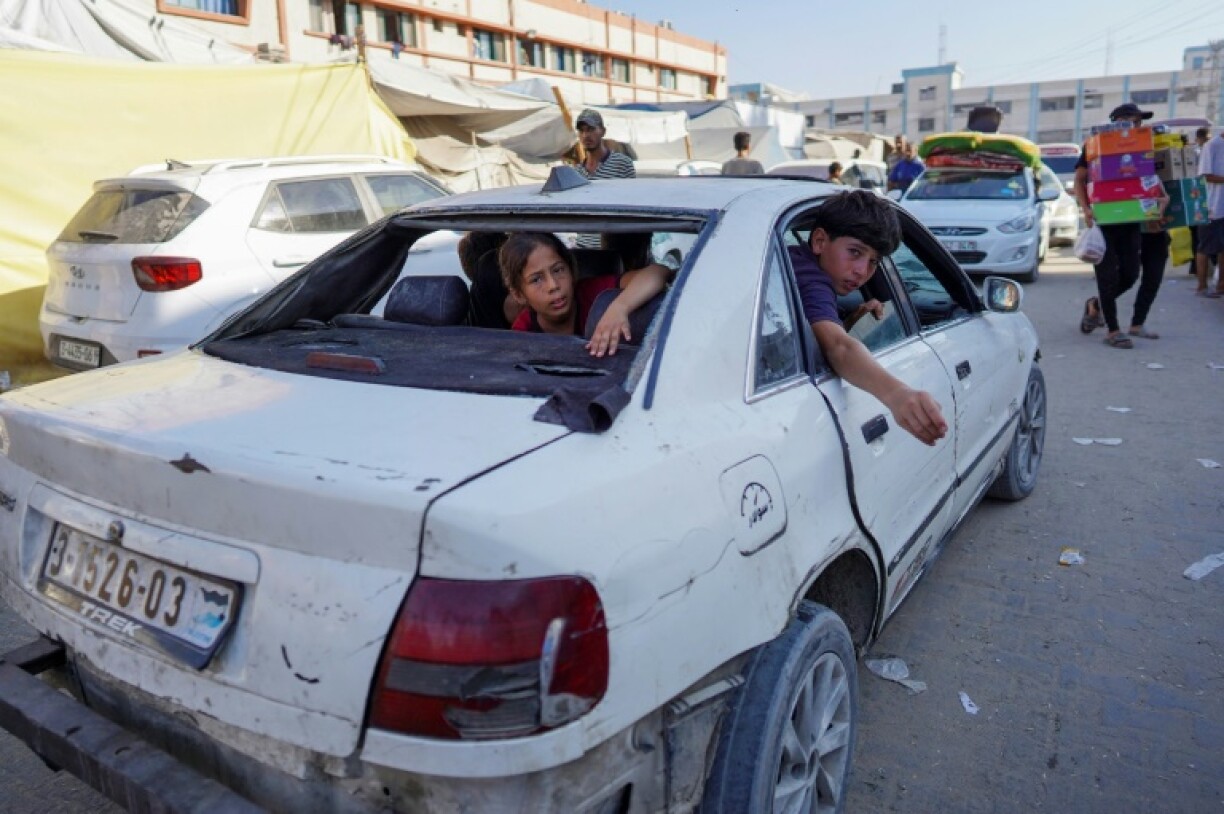 Des enfants sont assis dans une voiture endommagée à Khan Younès, dans le sud de la bande de Gaza, le 15 août 2024, sur fond de guerre entre Israël et le mouvement islamiste palestinien Hamas