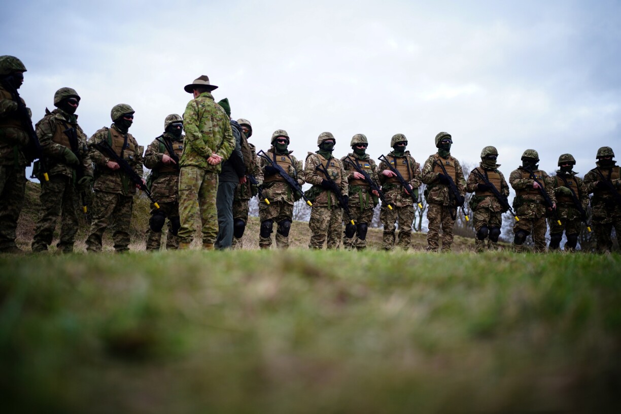 A member of the Australian Armed Forces speaks to Ukrainian soldier as they take part in a training session in Britain.