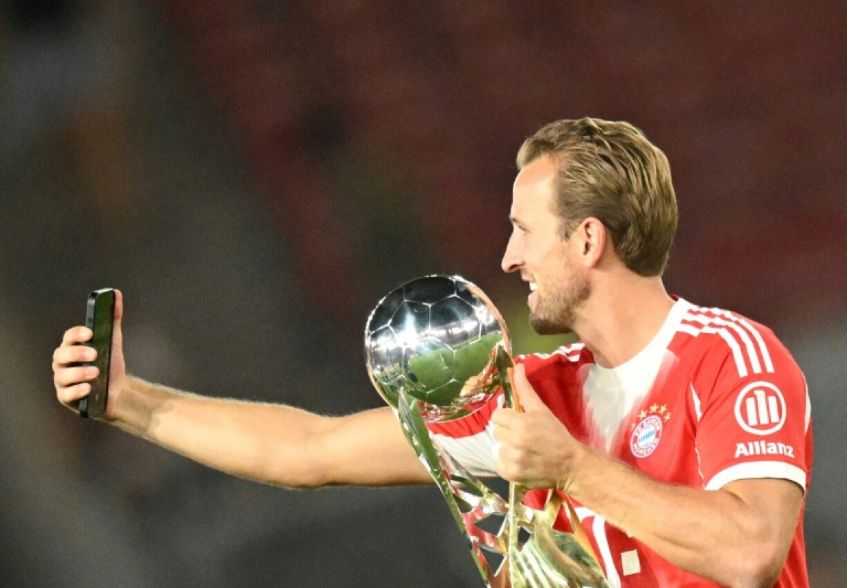 Bayern Munich's English forward Harry Kane (R) takes a selfie with the German Super Cup trophy