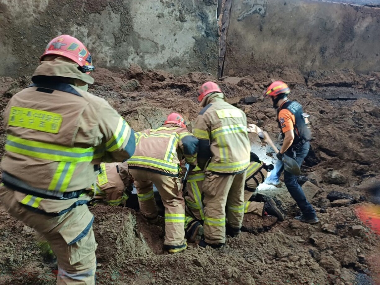 Rescue workers search for missing people after a 10-metre-high (33-foot) retaining wall from an overpass collapsed onto the road during a heavy rain in Osan