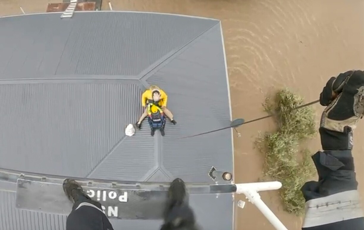 An Australian police helicopter rescues residents stranded on rooftops in flooded areas near the New South Wales town of Taree