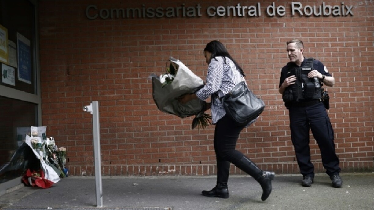 Une femme dépose des fleurs devant le commissariat de Roubaix en hommage aux trois policiers morts la veille dans un accident de la route, le 22 mai 2023 dans le Nord