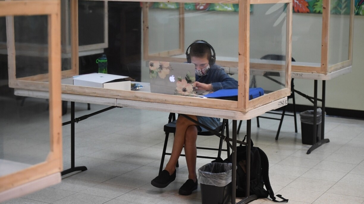 A student follows along remotely with their regular school teacher's online live lesson from a desk separated from others by plastic barriers at STAR Eco Station Tutoring & Enrichment Center on September 10, 2020 in Culver City, California.