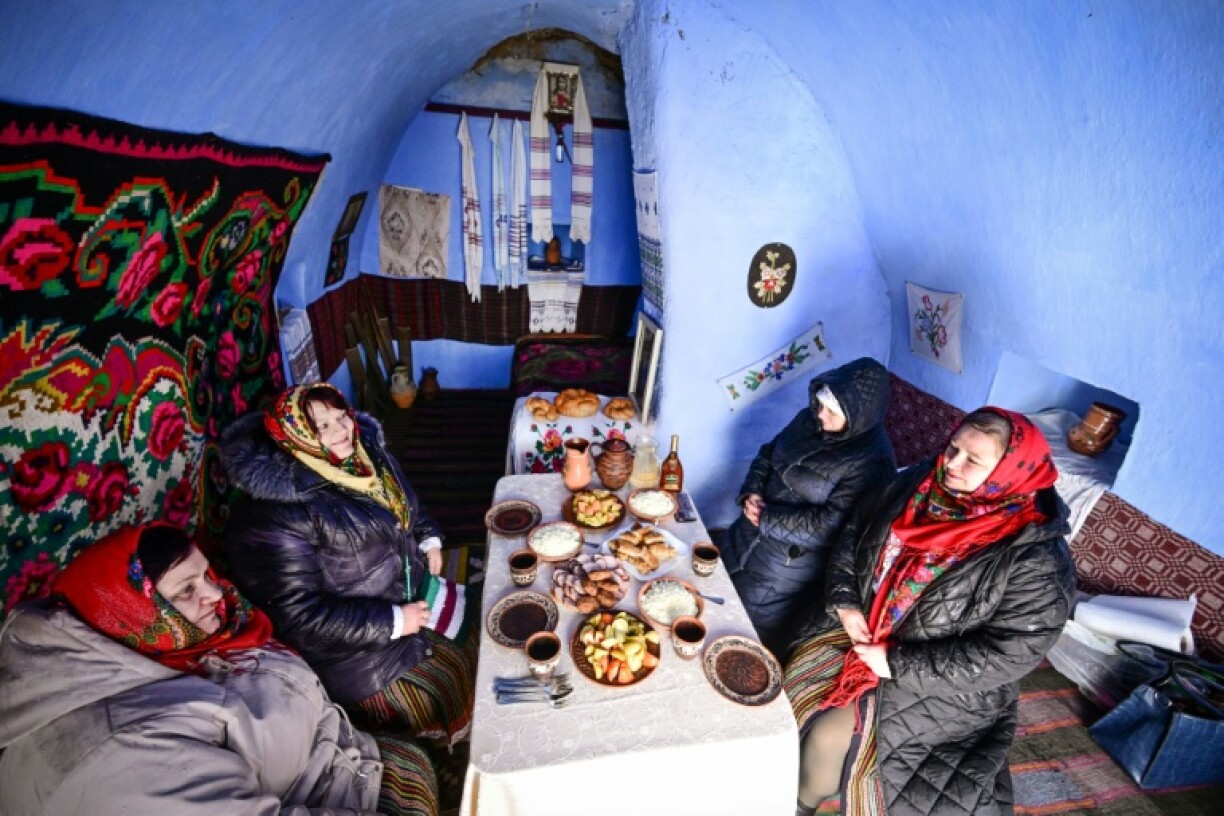 Des femmes du village de Rogojeni, en costumes traditionnels, prennent un repas à l'intérieur d'une maison-musée "basca", le 4 janvier 2026 en Moldavie