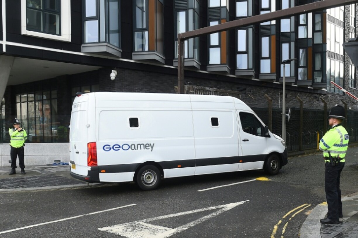 A prison van passes police officers outside Liverpool Magistrates' Court as a 53-year-old former Marine was due to appear for the first time facing seven charges of driving into crowds of football fans