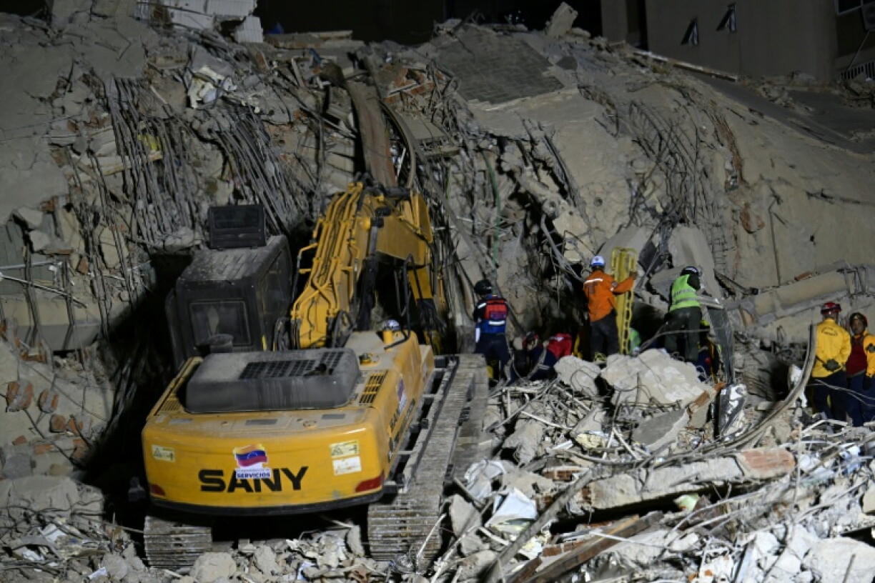 Des équipes de secours utilisent des engins de chantier sur le site d'un immeuble effondré à Caracas, le 25 juin 2026, à la suite de séismes