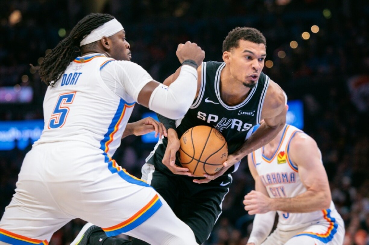 Victor Wembanyama (c) tente de passer la défense de Luguentz Dort (g) lors du match NBA entre les San Antonio Spurs et l'Oklahoma City Thunder, le 25 décembre 2025 à Oklahoma City