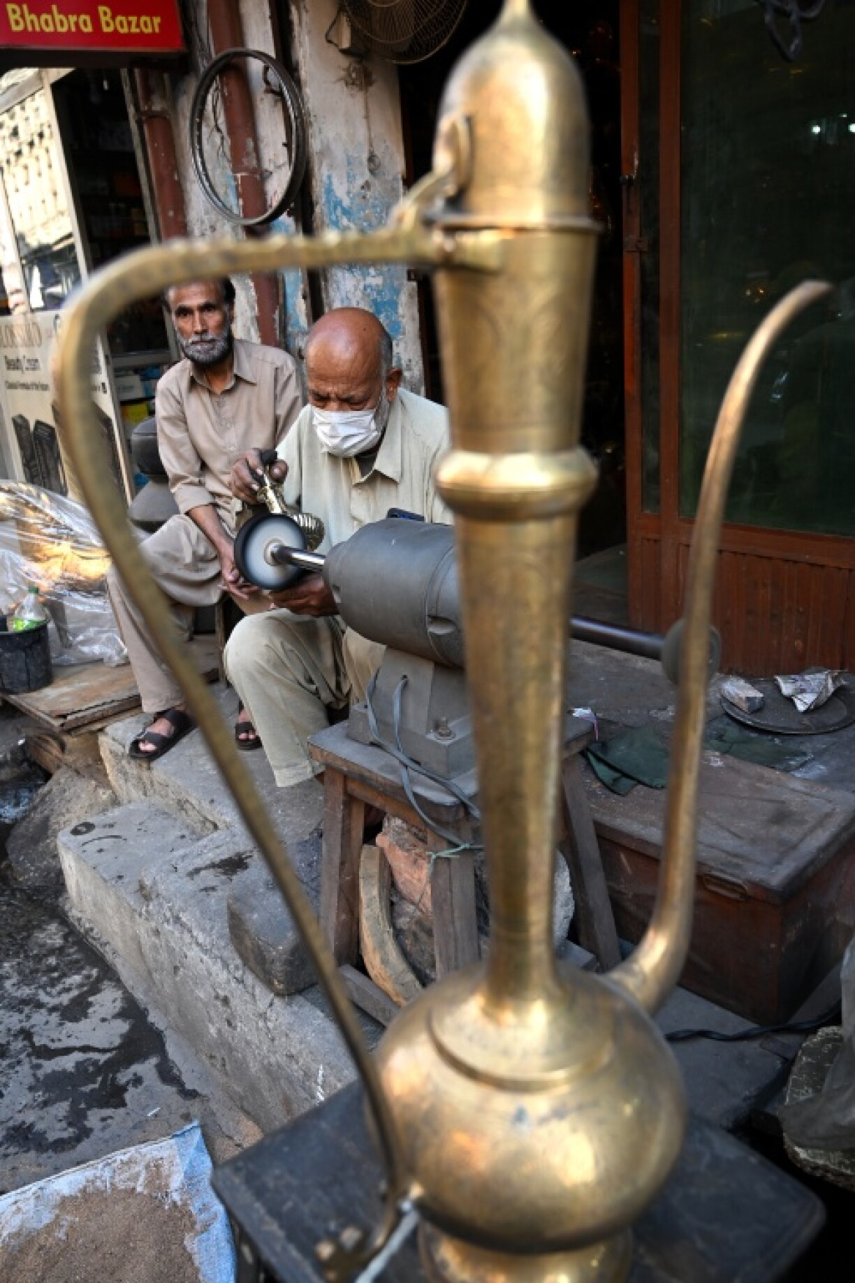 Antique dealer Ahsan Shakeel polishes an artefact outside his shop selling vintage items in Rawalpindi