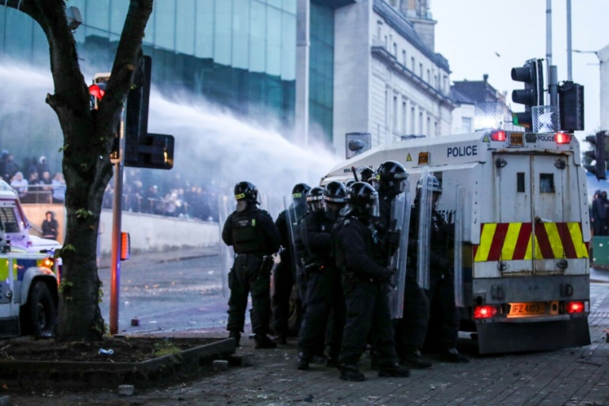 Police officers gather behind a water canon vehicle as hundreds of protestors demonstrated in Ballymena, Northern Ireland