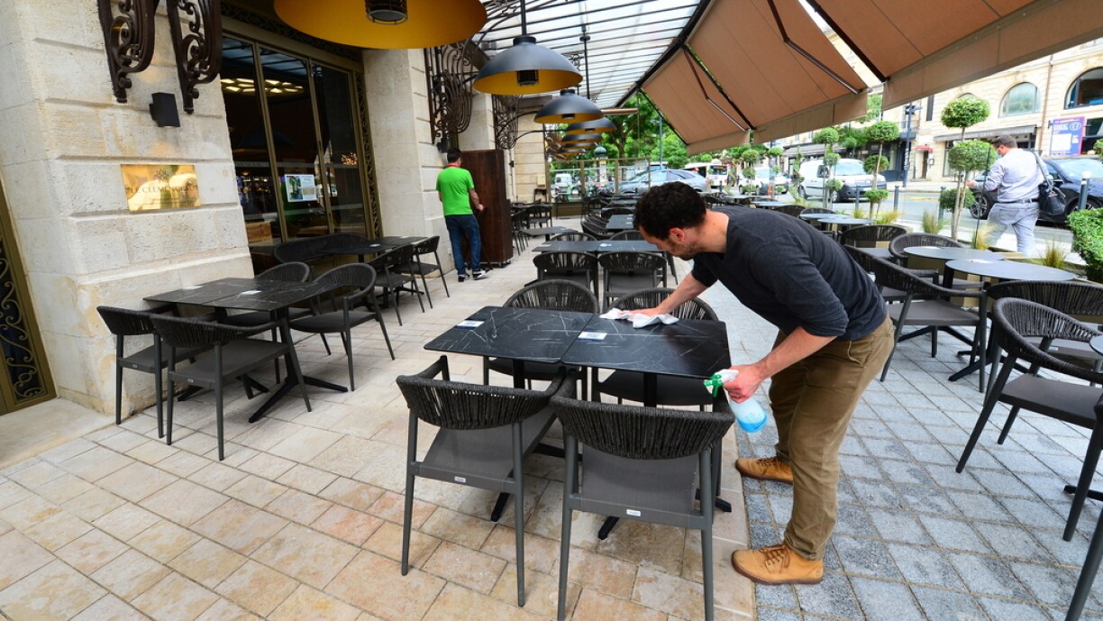 An employee cleans the tables on the outdoor terrasse of 'Le Clemenceau' restaurant in Bordeaux on May 18, 2021, ahead of the reopening of restaurant and cafe terrasses scheduled for May 19, 2021 after a closure aimed at curbing the spread of the Covid-19 pandemic.
