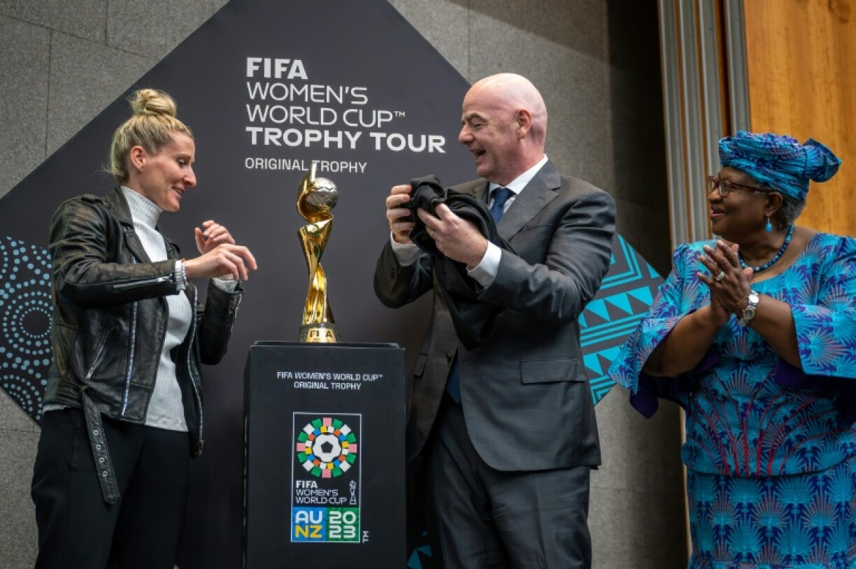 Le président de la FIFA, Gianni Infantino, entre l'attaquante allemande Anja Mittag (à gauche) et la directrice générale de l'Organisation mondiale du commerce Ngozi Okonjo-Iweala dévoilant le trophée de la Coupe du monde féminine le 1er mai 2023 au siège de l'OMC à Genève